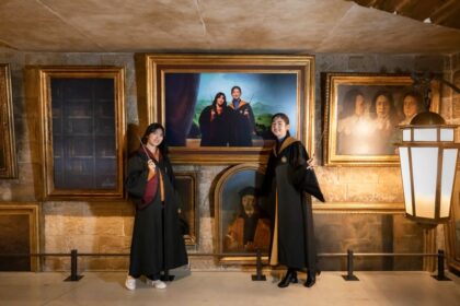 People posing beside moving portrait displays at Warner Bros. Studios Japan